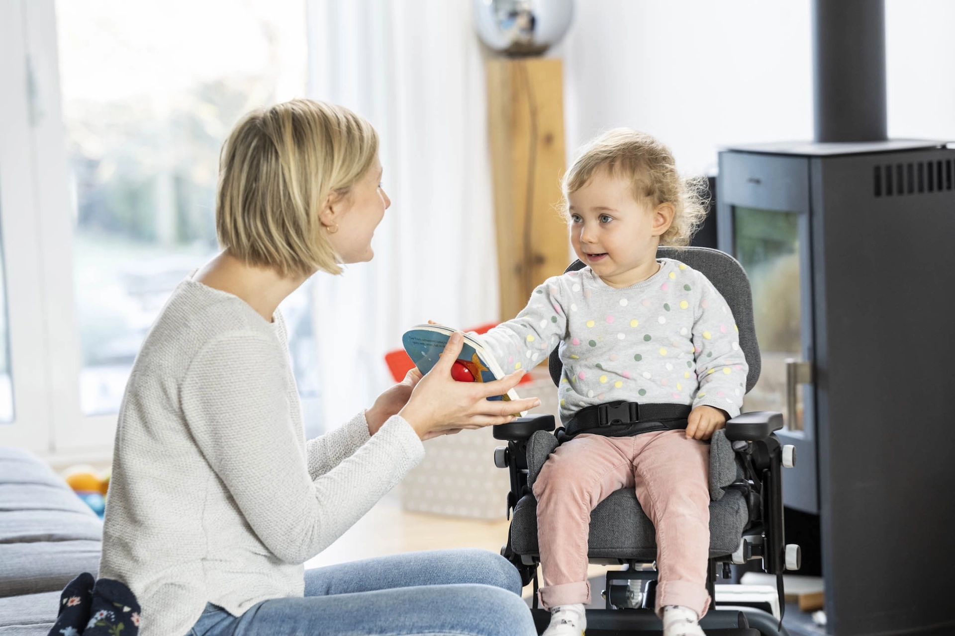 Mutter spricht mit Kind in orthopaedischem Stuhl